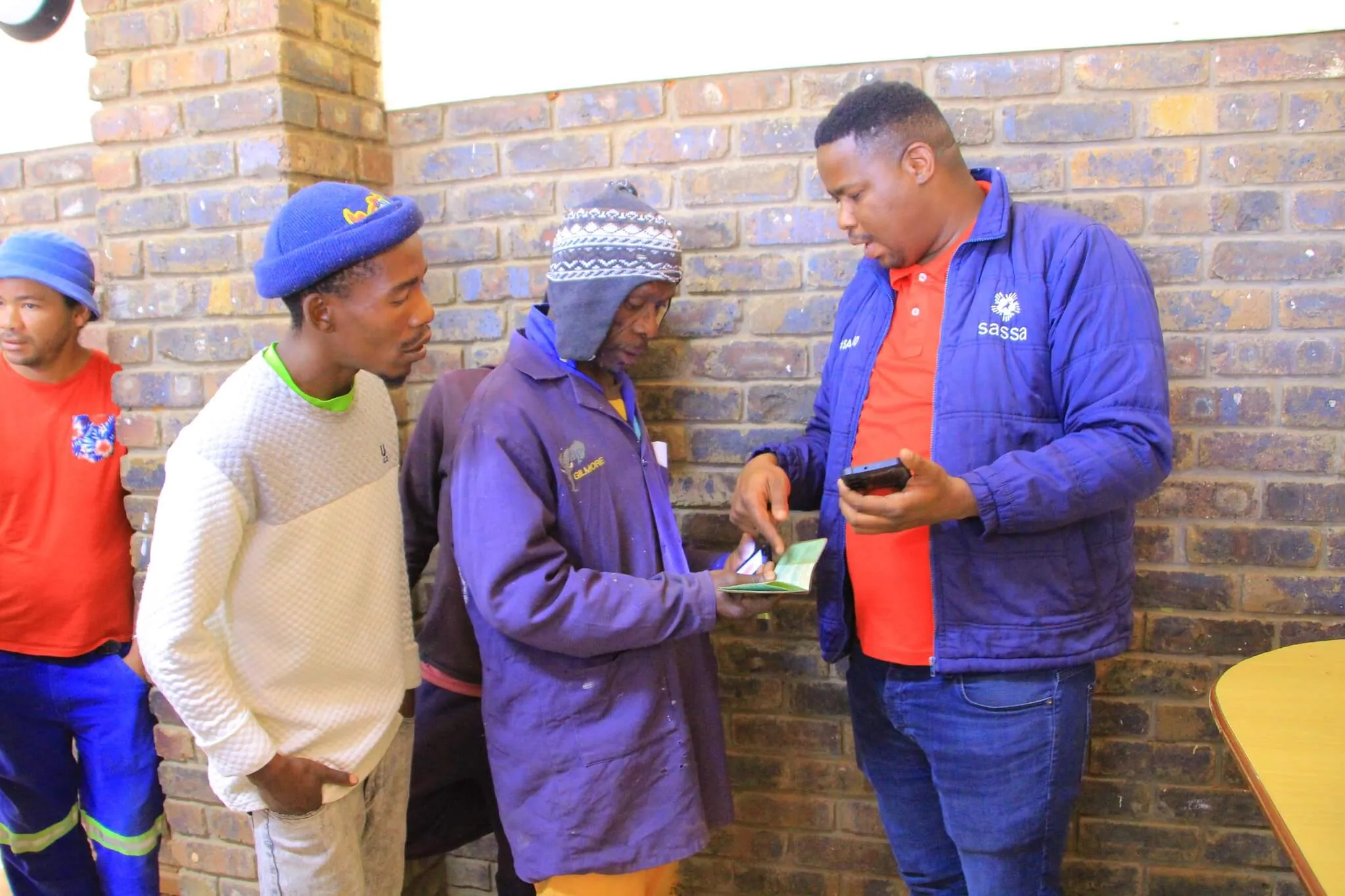 SASSA officer verifying a beneficiary’s ID documents before updating phone number at the office, SASSA Warns Update SRD R370 Contact Details by 19 September 2025 to Avoid Missed Payments